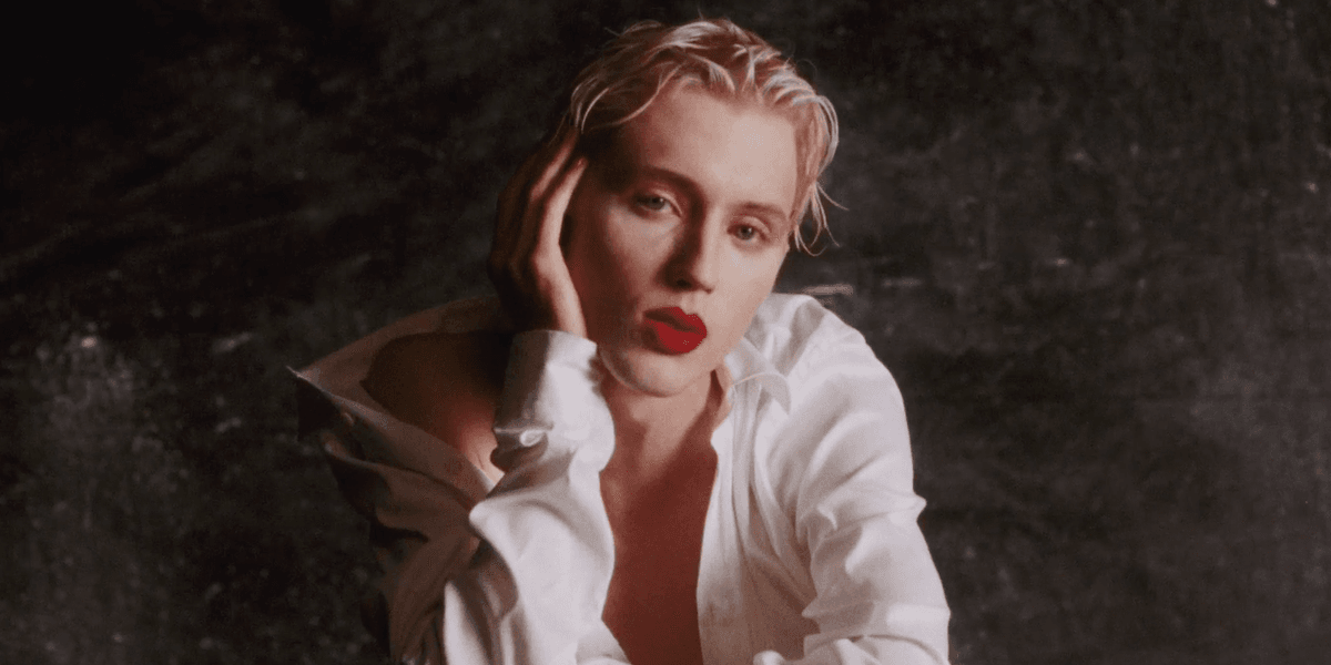 Troye Sivan in a white shirt and red lipstick in Bloom